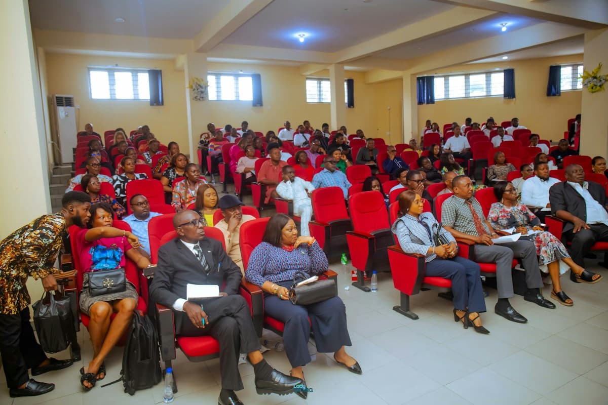 An audience seated in red chairs at a conference presentation